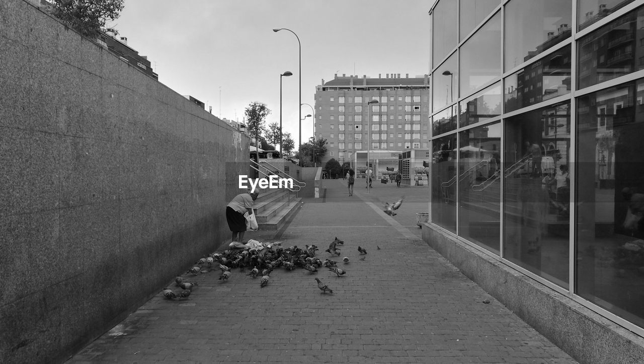 MAN WALKING ON STREET BY ROAD AGAINST SKY