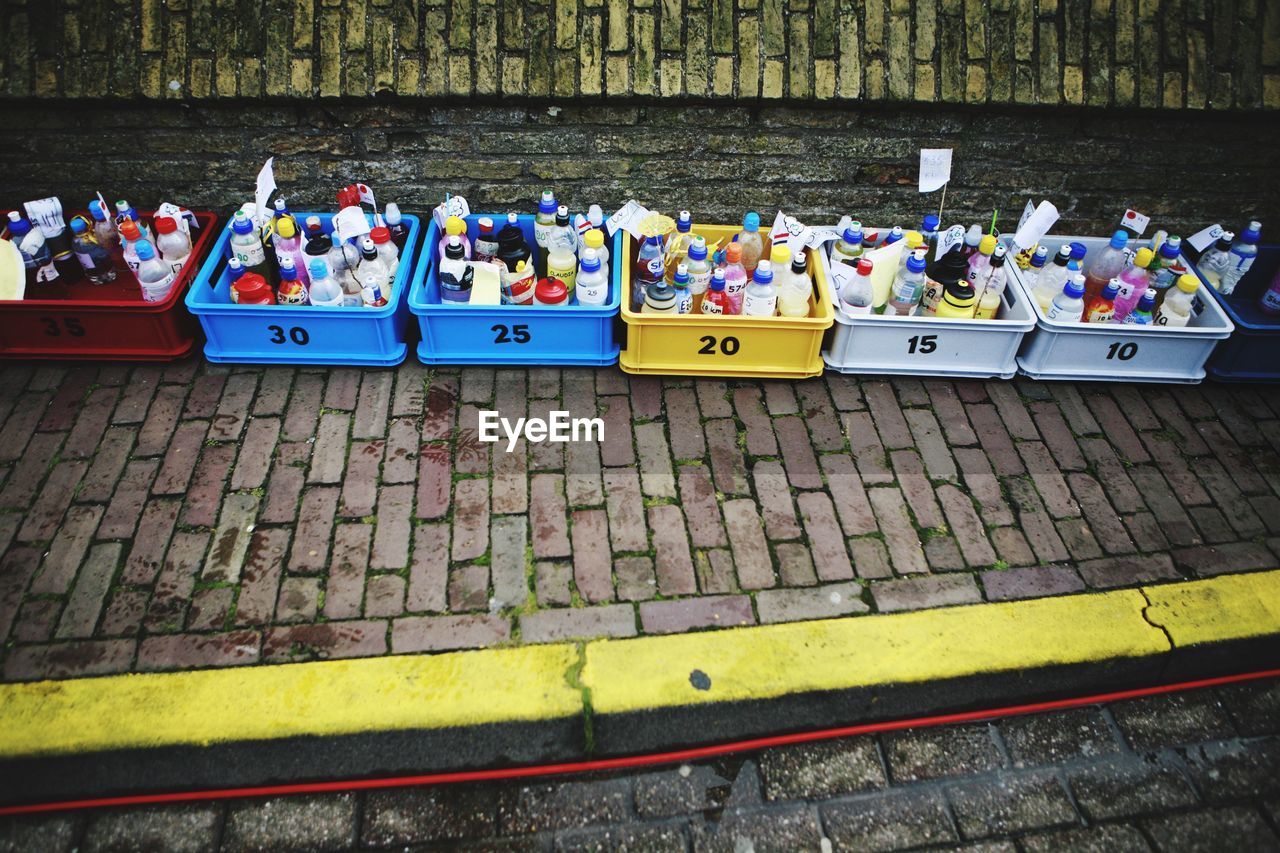 High angle view of drinks bottle in crates on sidewalk against wall