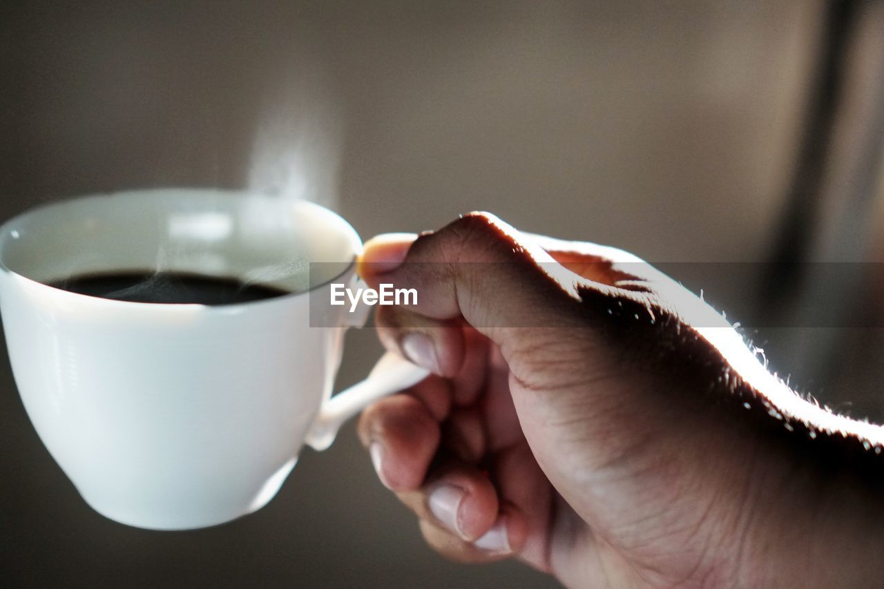 CLOSE-UP OF PERSON HOLDING COFFEE CUP