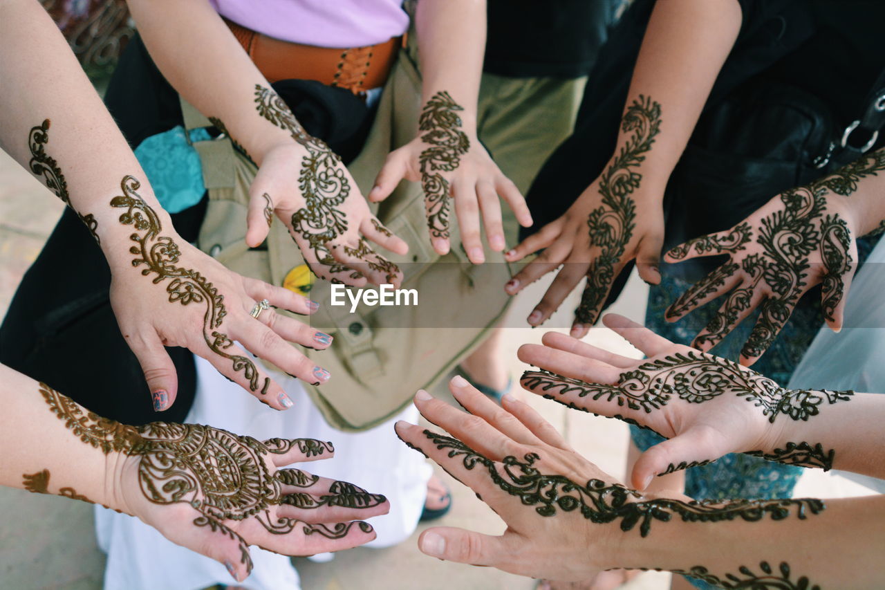 High angle view of people with henna tattoo on hands