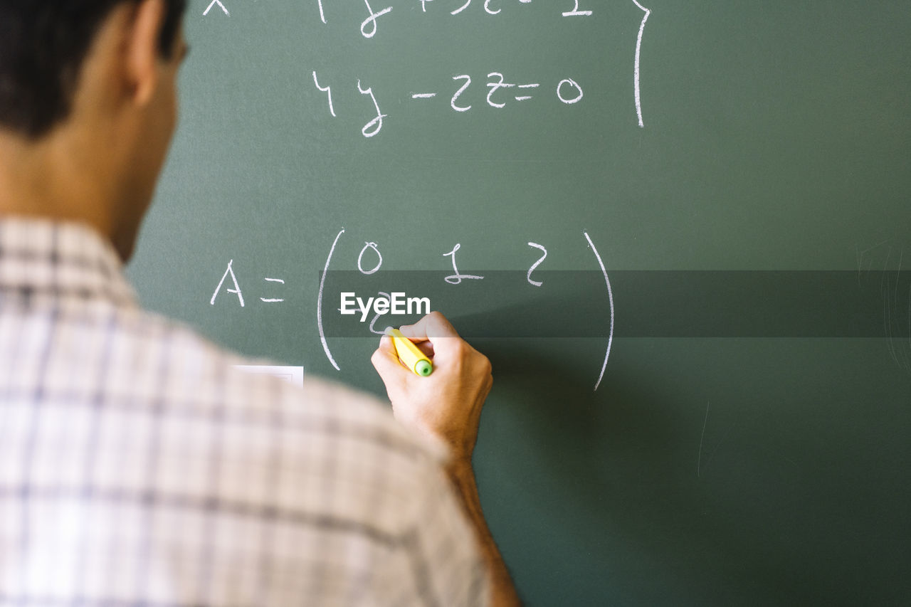 Math teacher solving problems on chalkboard