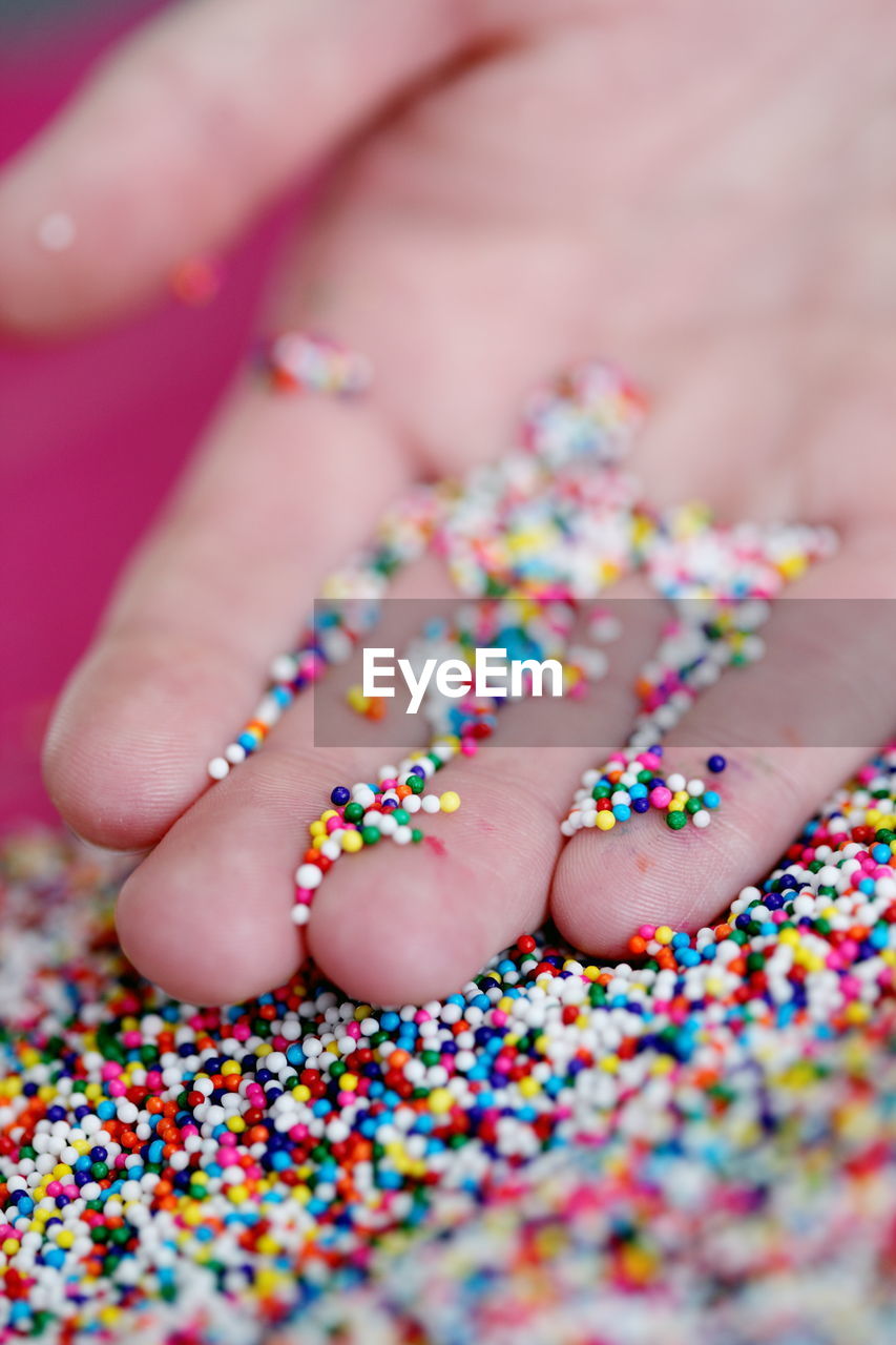 Cropped hand with colorful sprinkles on table