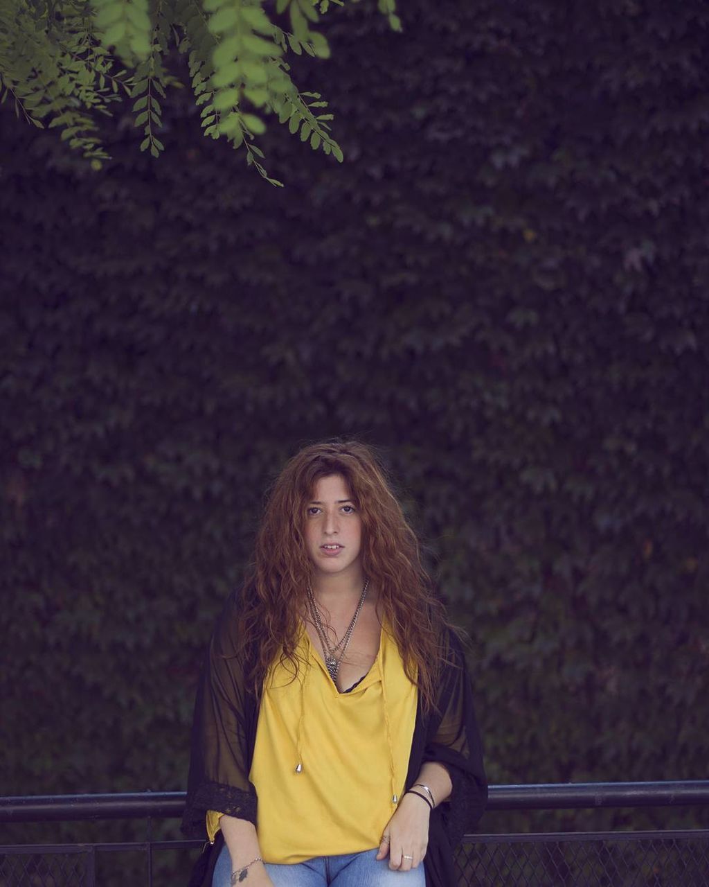 Portrait of young woman with long hair against ivies