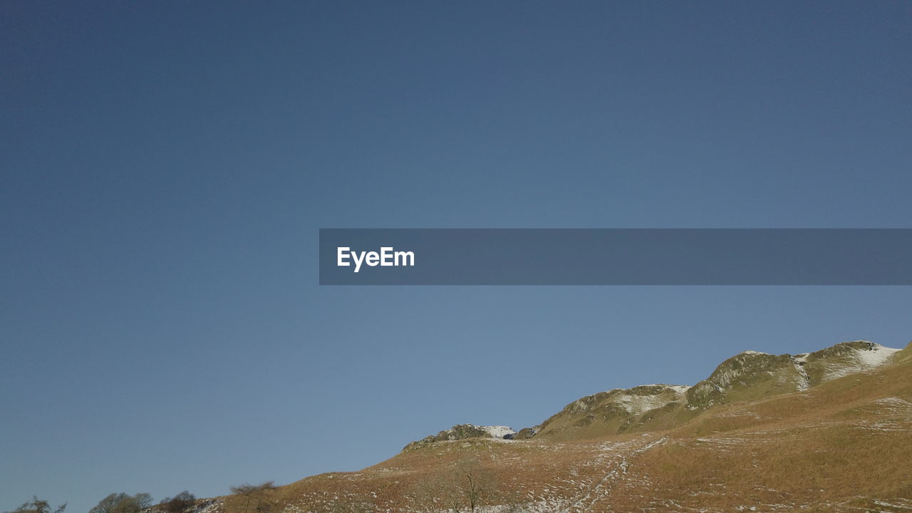 LOW ANGLE VIEW OF ROCK FORMATION AGAINST CLEAR BLUE SKY