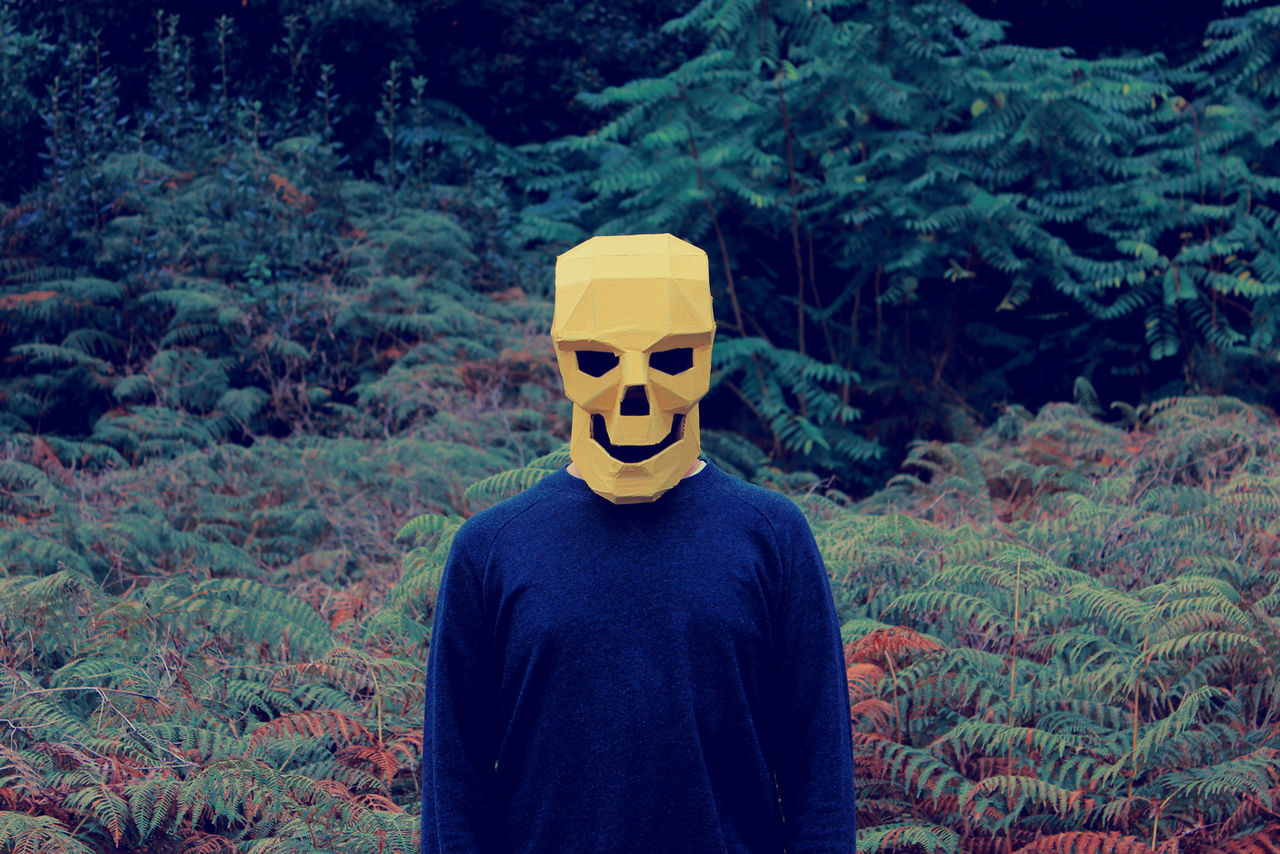 Close-up of man wearing skull mask against trees