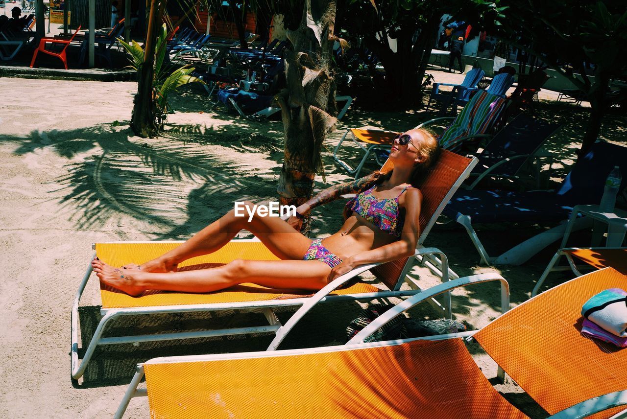 Woman sitting on lounge chair during sunny day