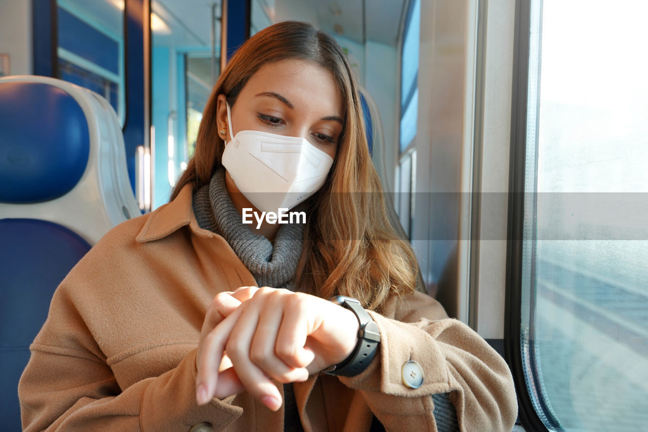 Woman on train looking at smartwatch her train is stopped on railroad in the middle of nowhere