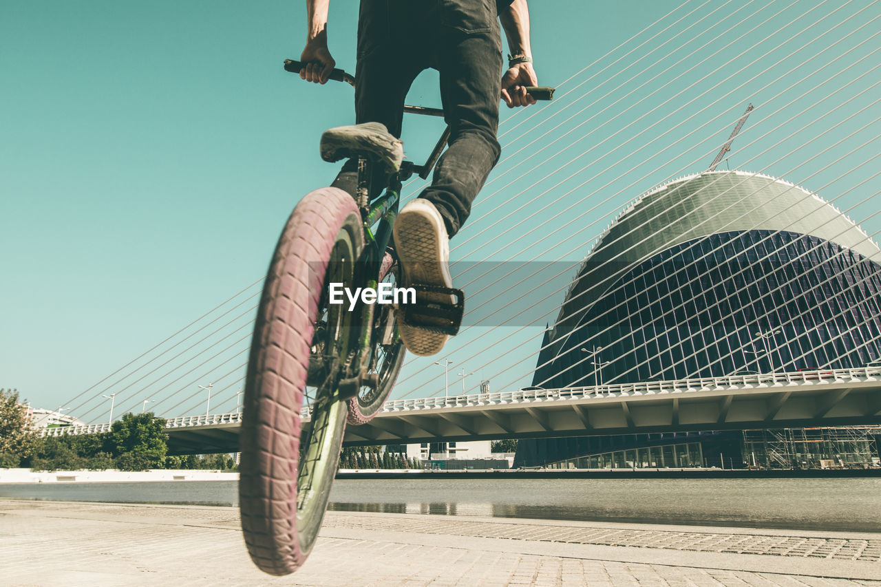 Low section of man riding bmx cycle on footpath in city