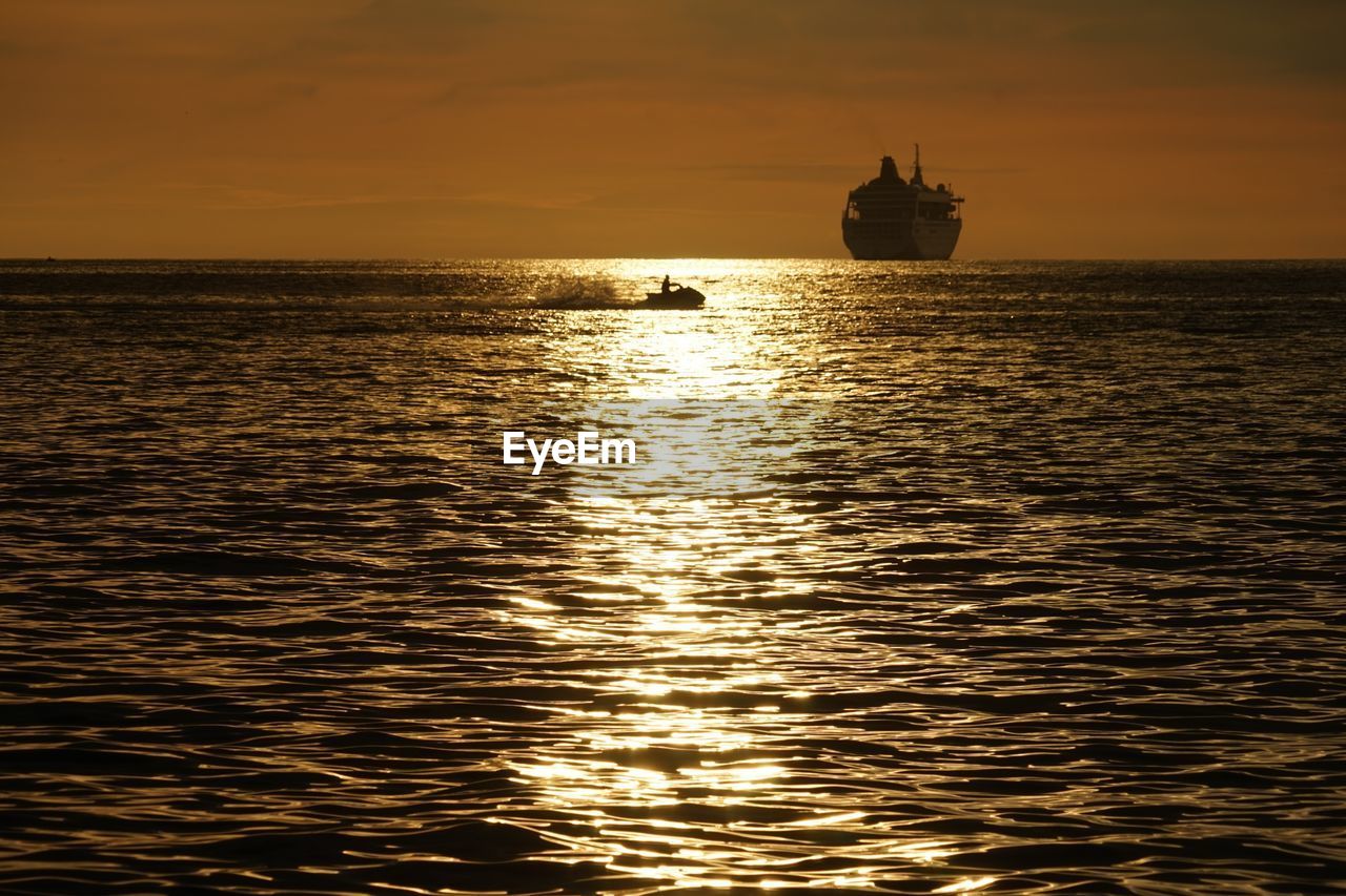 SILHOUETTE SHIP SAILING IN SEA AGAINST SKY DURING SUNSET