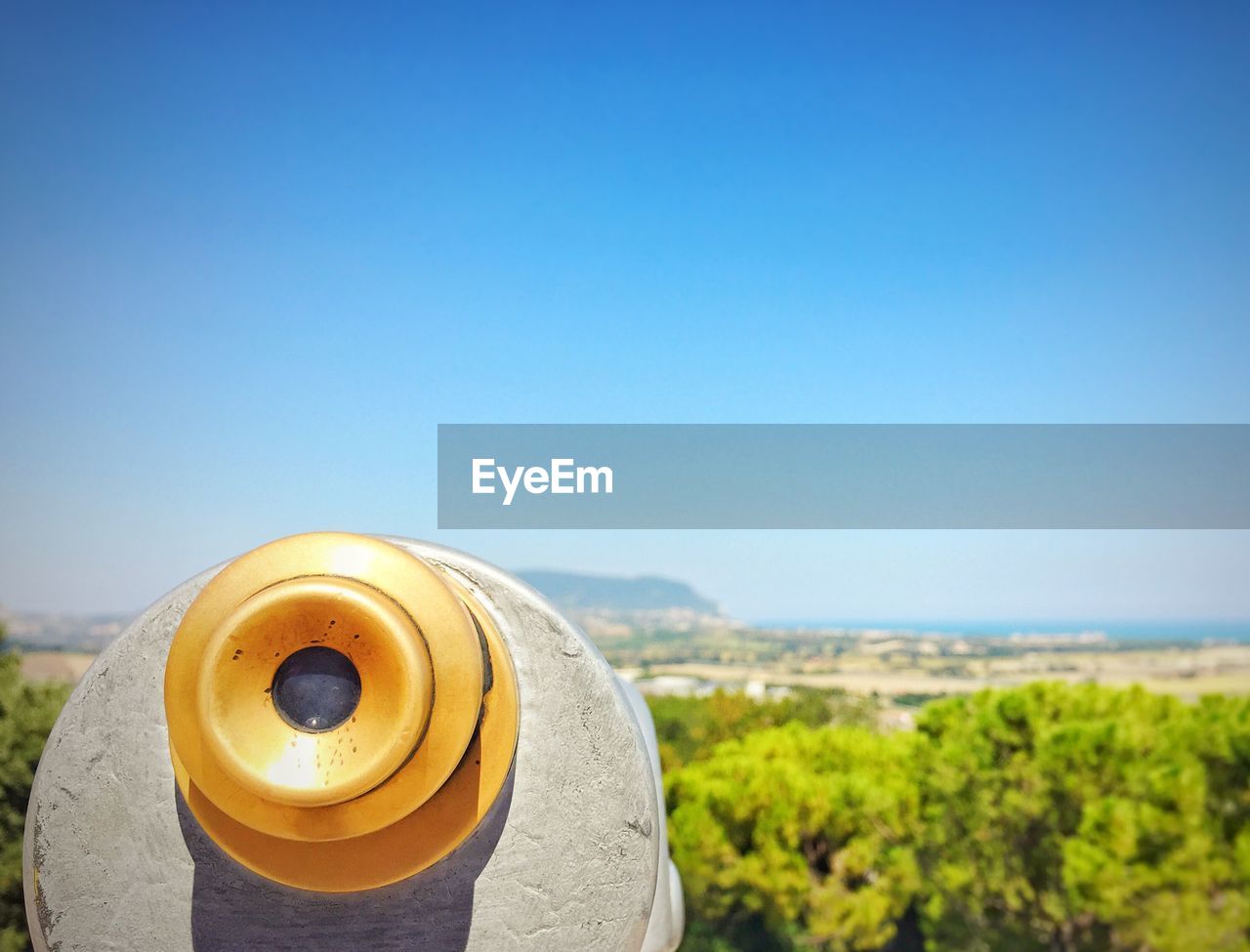 Close-up of coin-operated binoculars by sea against clear blue sky