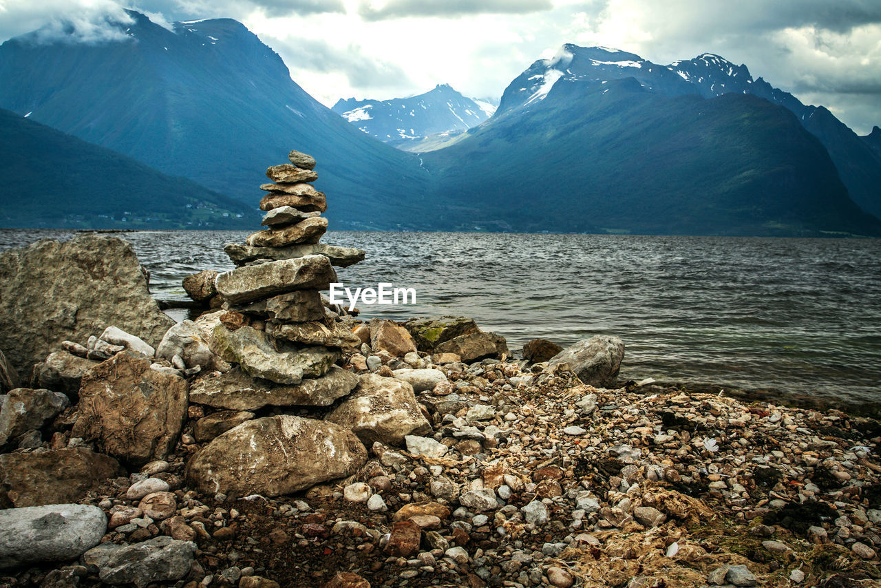 STACK OF ROCKS ON SHORE AGAINST MOUNTAIN