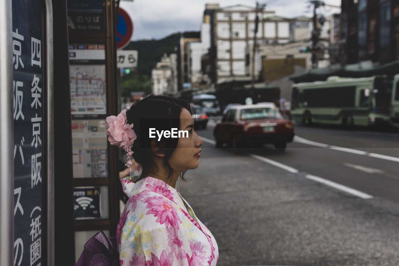 Woman looking away on road in city