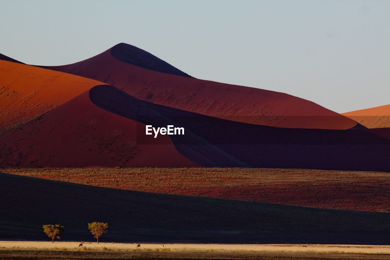 Scenic view of desert against clear sky on sunny day