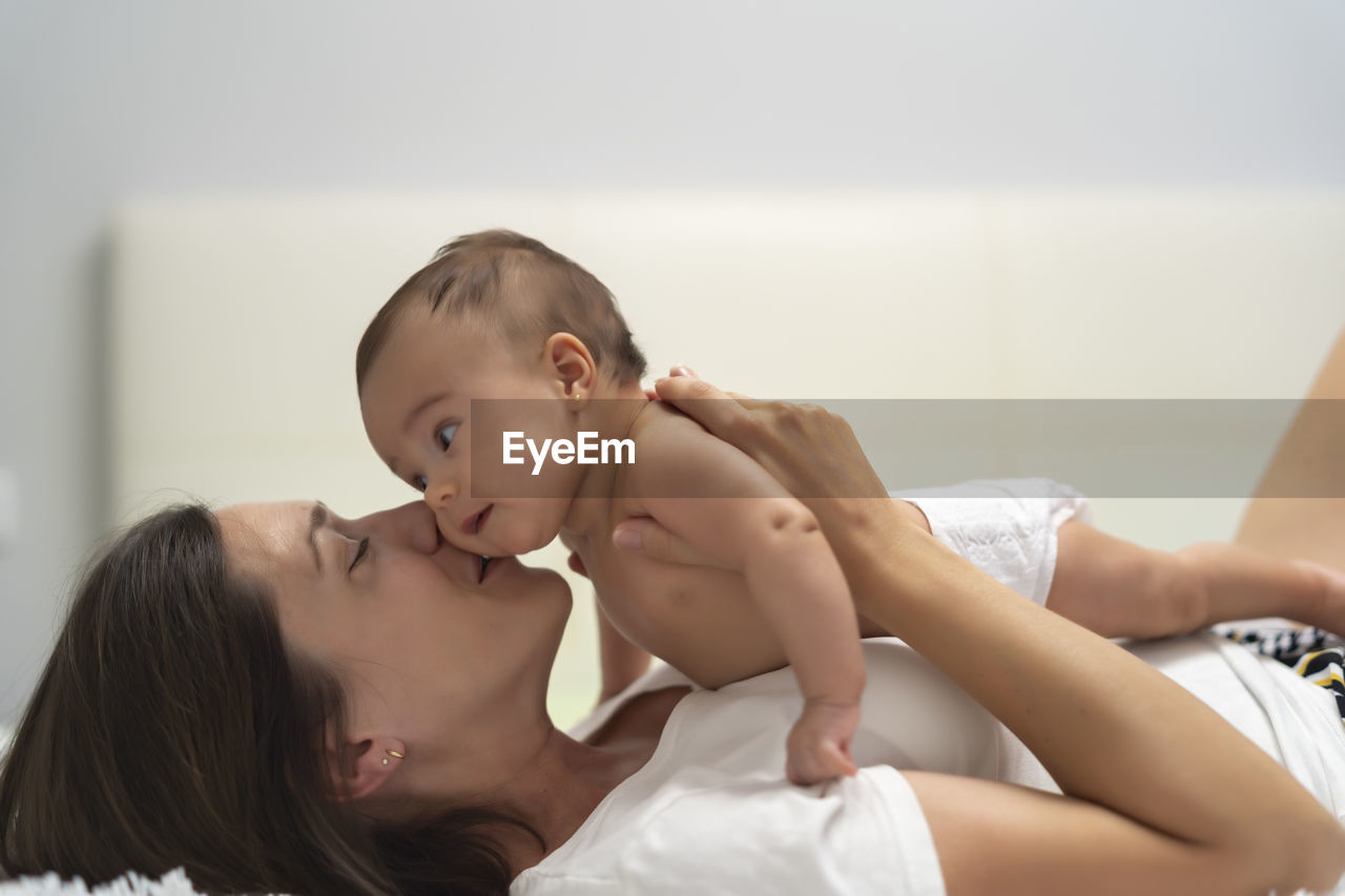 Mother kissing her baby in bed