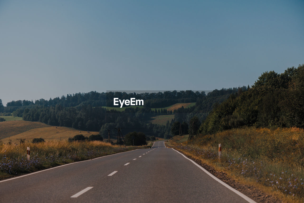 Road passing through landscape against clear sky