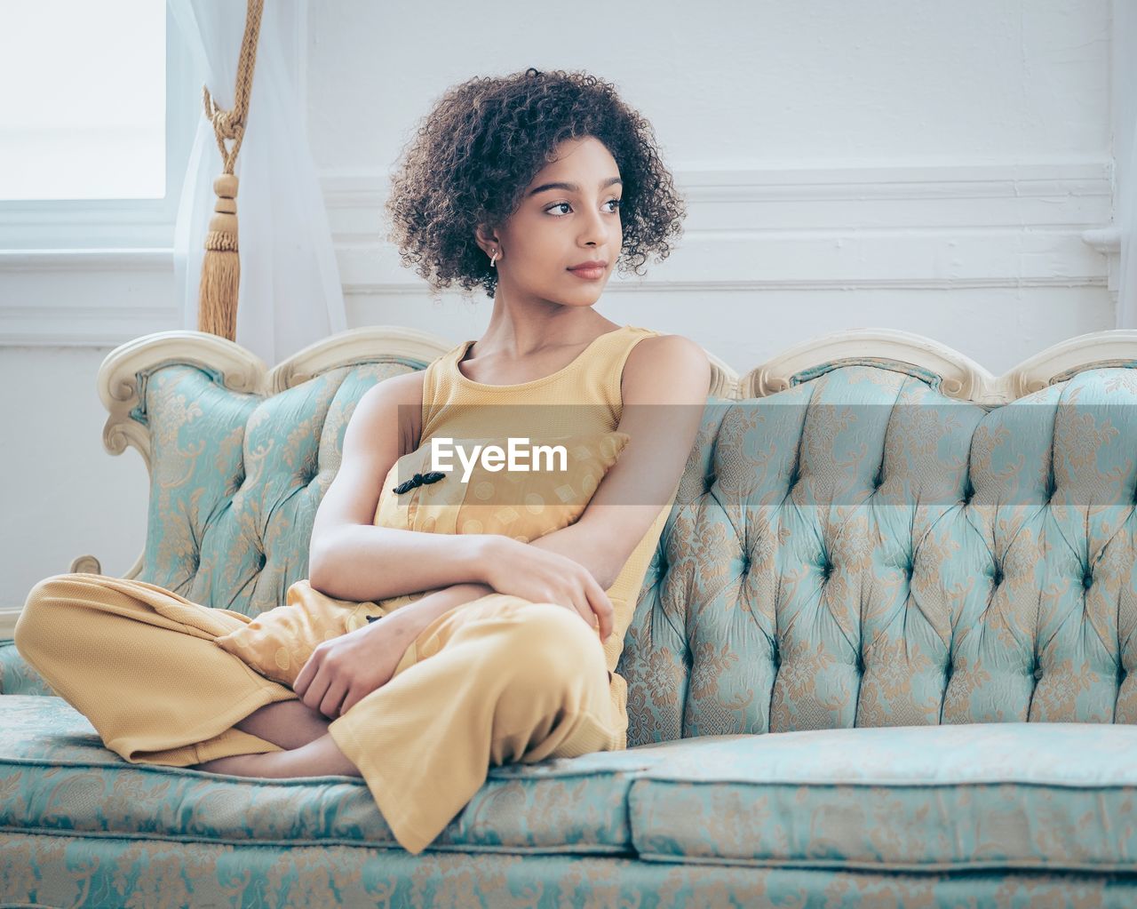 Young woman looking away while sitting on sofa at home