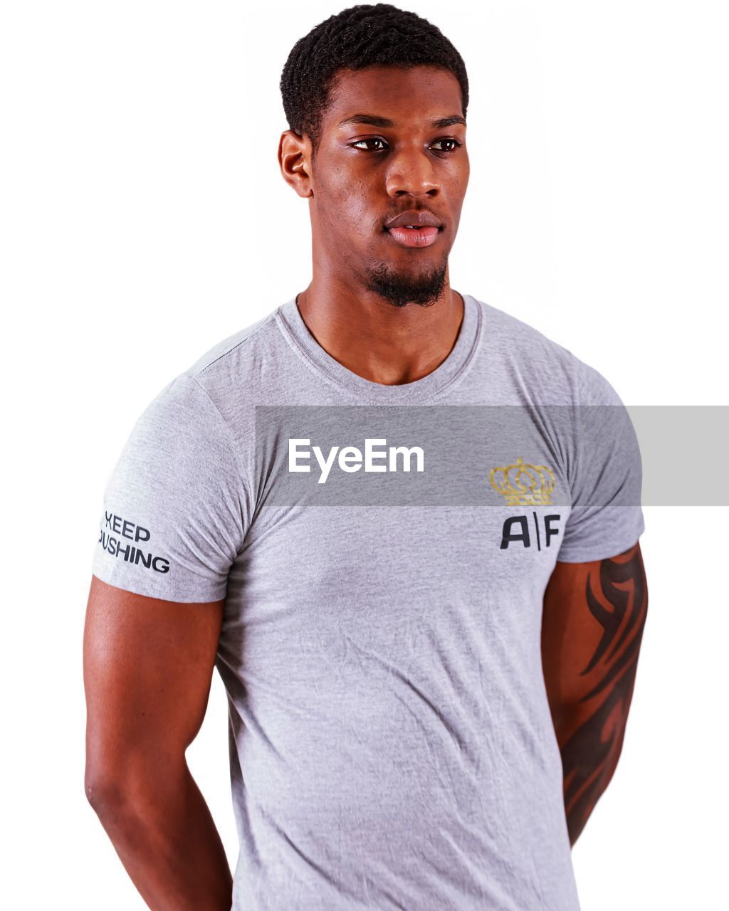 t-shirt, one person, studio shot, portrait, casual clothing, white background, adult, sleeve, men, active shirt, young adult, indoors, waist up, cut out, arm, clothing, standing, looking at camera, lifestyles, relaxation, pocket, muscular build, athlete, emotion, front view, shaved head, facial hair, looking, copy space, masculinity, smiling, strength, beard, sports, happiness