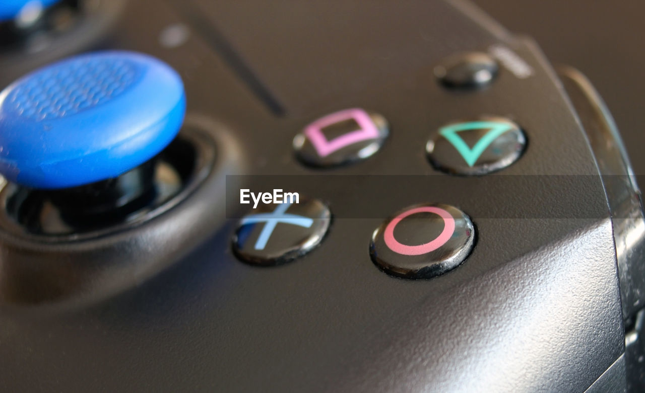 A close up of the iconic sony play station buttons on a wireless controller or remote