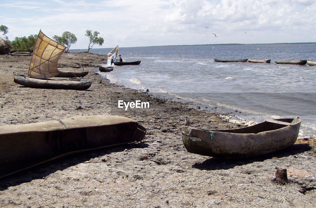 BOATS MOORED ON SHORE AGAINST SKY