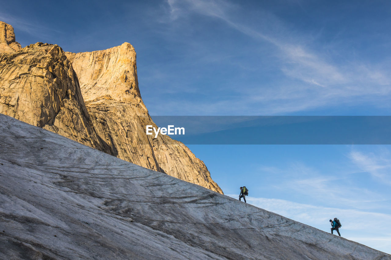 Climbers hike up glacier towards mount asgard, baffin island.