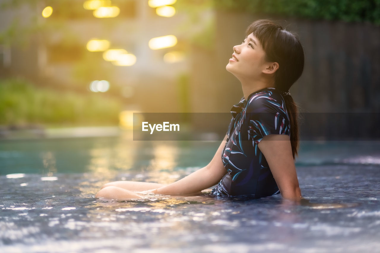 Side view of woman sitting in swimming pool