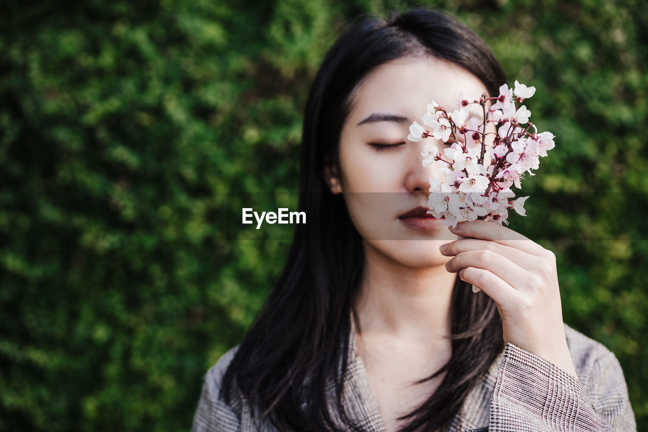 Beautiful chinese asian woman holding almond tree flowers.spring. selective focus on flowers