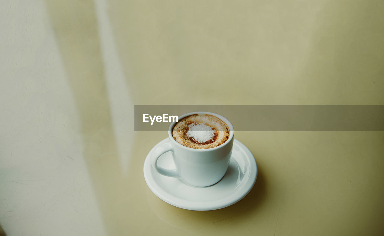 Cup of coffee with white sugar on the top on the table