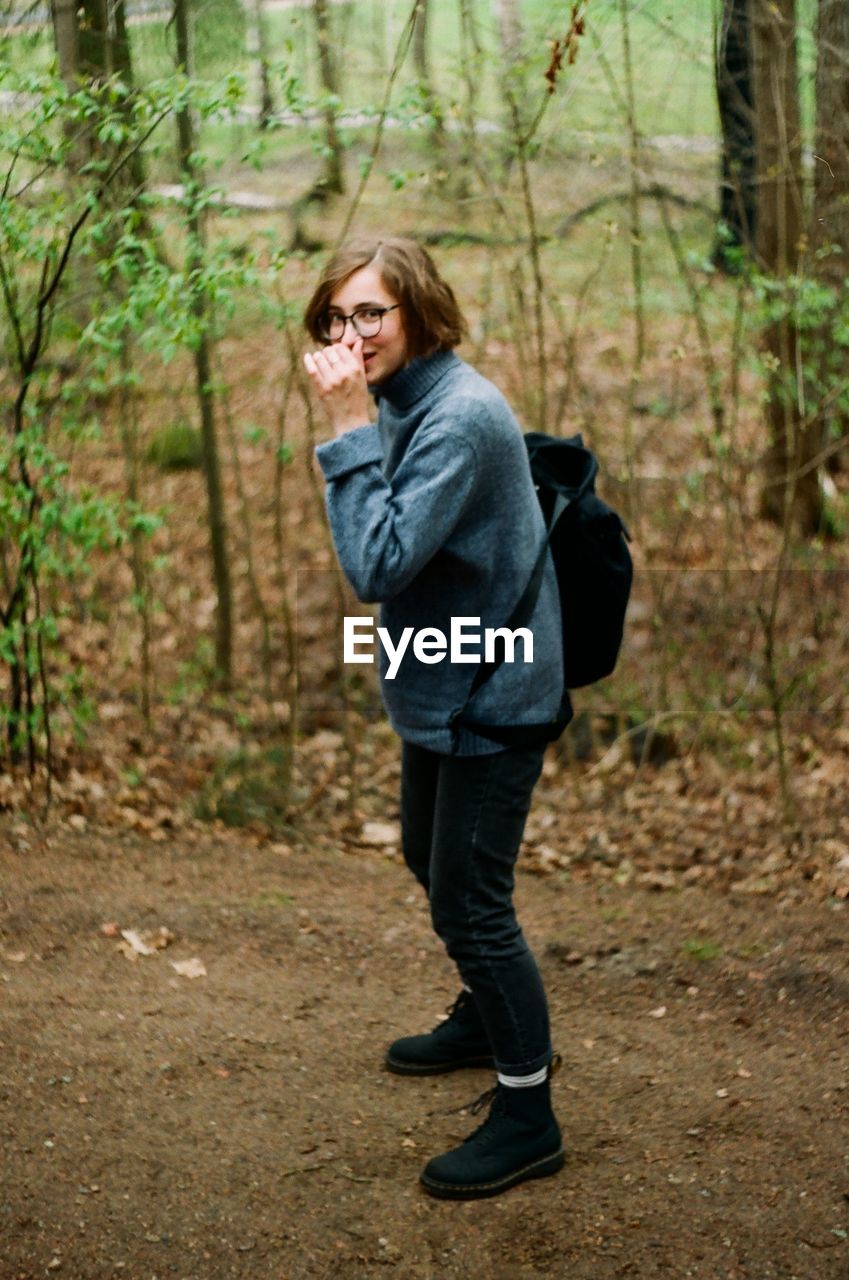 Side view of woman standing in forest