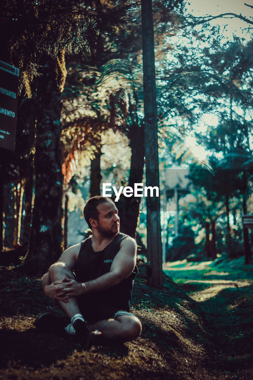 Thoughtful man sitting on land in forest