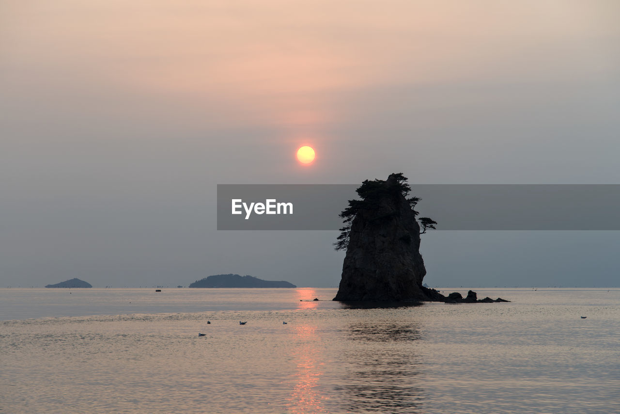 Rock formations amidst sea against sky during sunset