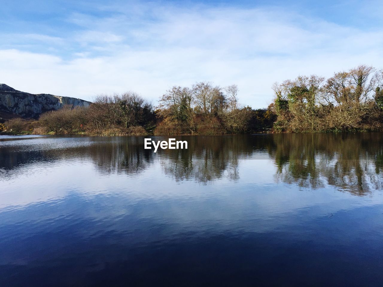 REFLECTION OF TREES ON LAKE AGAINST SKY