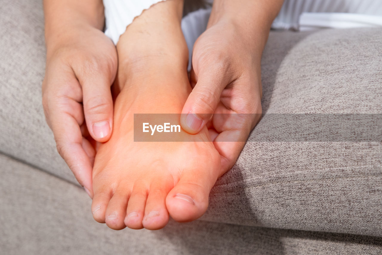 Cropped hands of person holding swollen feet