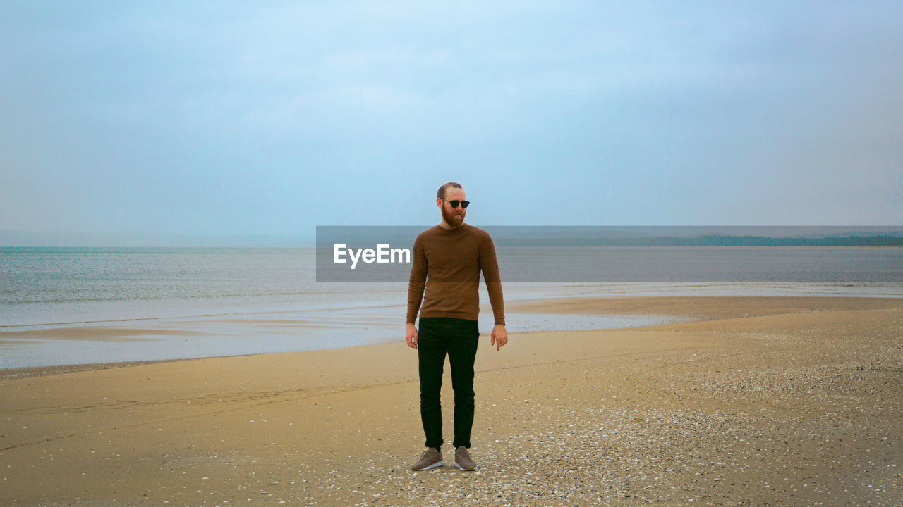 Full length of man standing at beach against sky