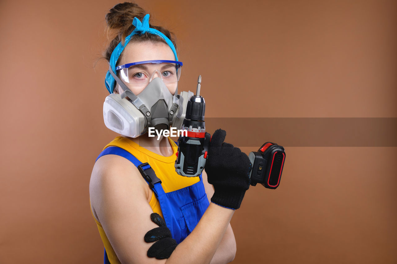 Gender equality. portrait of a young woman in a uniform, goggles and a respirator working in a