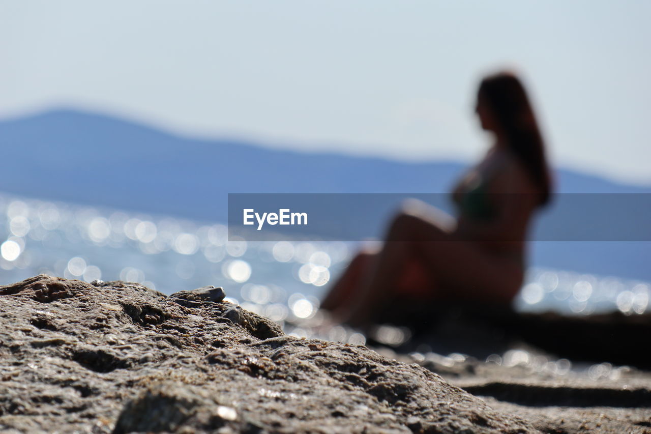 WOMAN SITTING ON ROCK