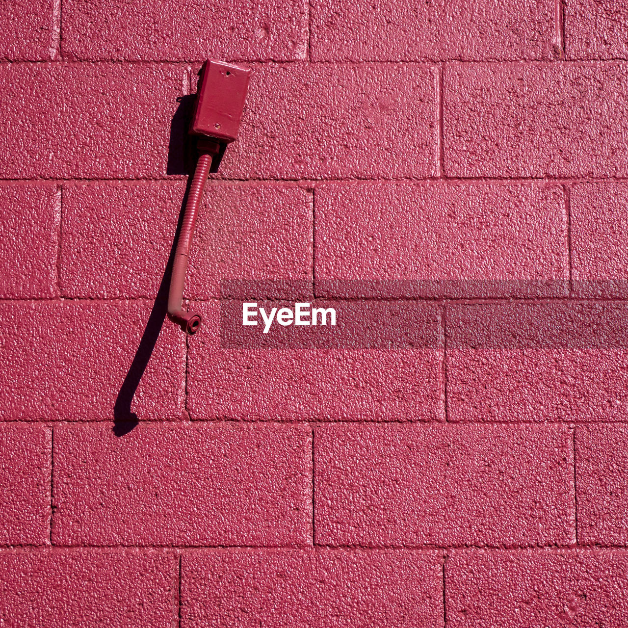 LOW ANGLE VIEW OF BRICK WALL WITH RED UMBRELLA