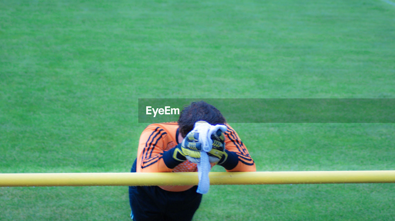 High angle view of man leaning on railing at playing field