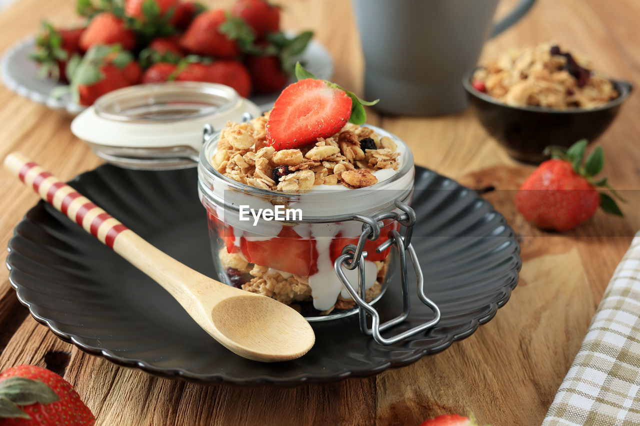 Strawberry parfait with granola and yoghurt, close up on wooden table. summer snack concept