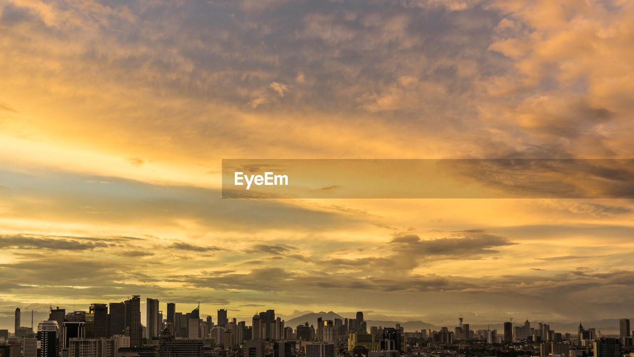 View of cityscape against cloudy sky during sunset