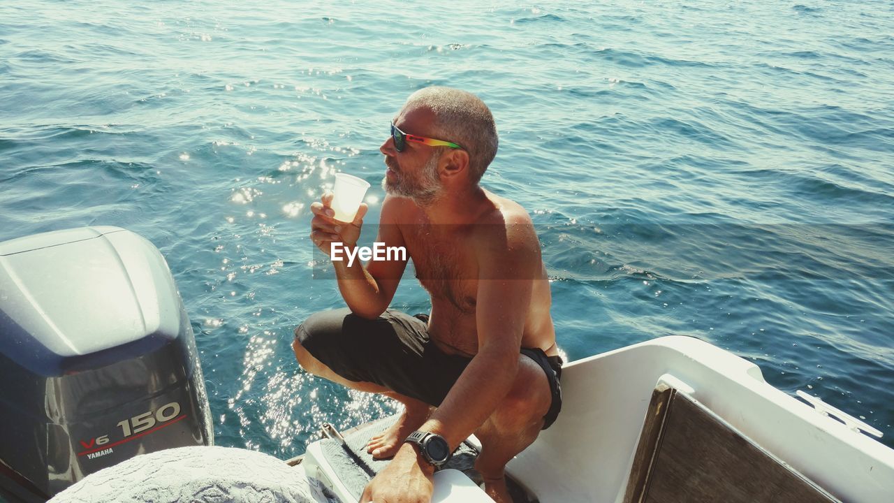 MAN SITTING ON BOAT IN SEA