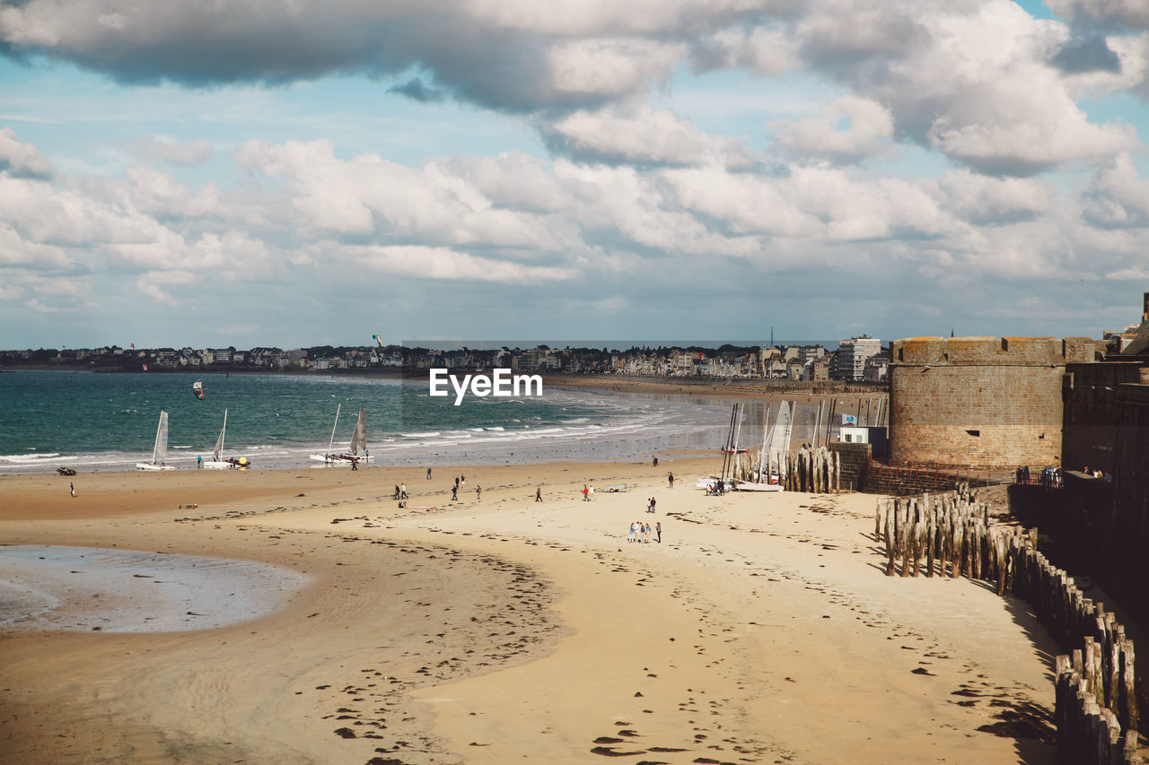 Scenic view of beach against cloudy sky in city