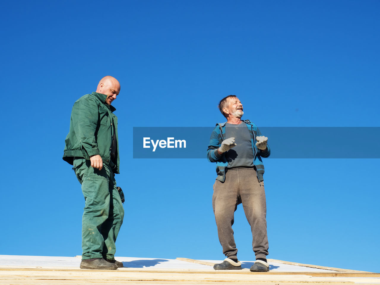 Full length of father and son standing on land against clear blue sky