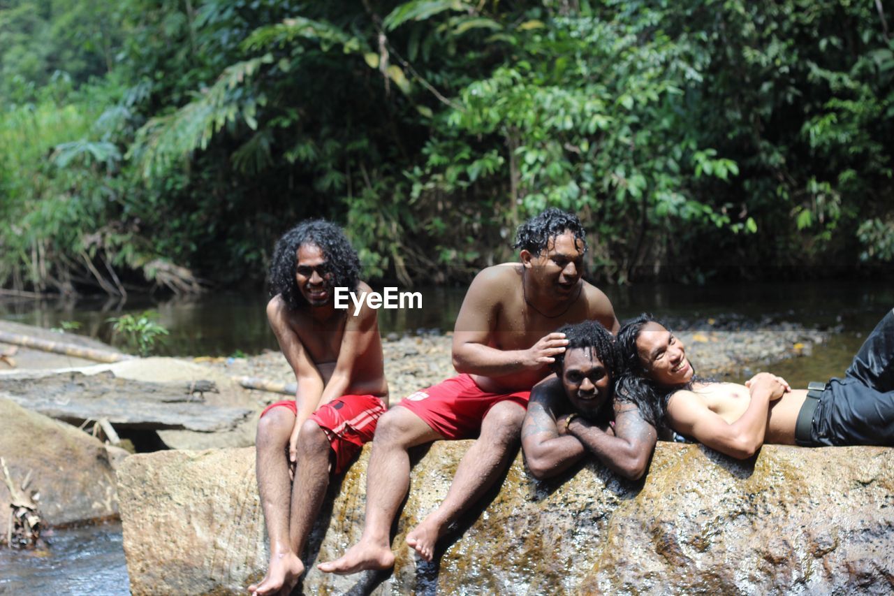 Happy men on rock in forest