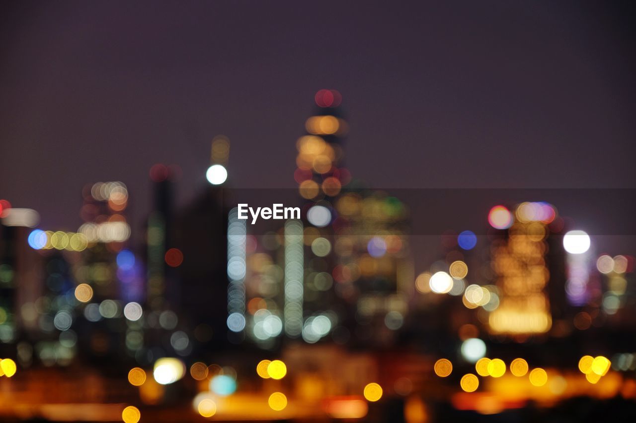 DEFOCUSED IMAGE OF ILLUMINATED CITY AT NIGHT