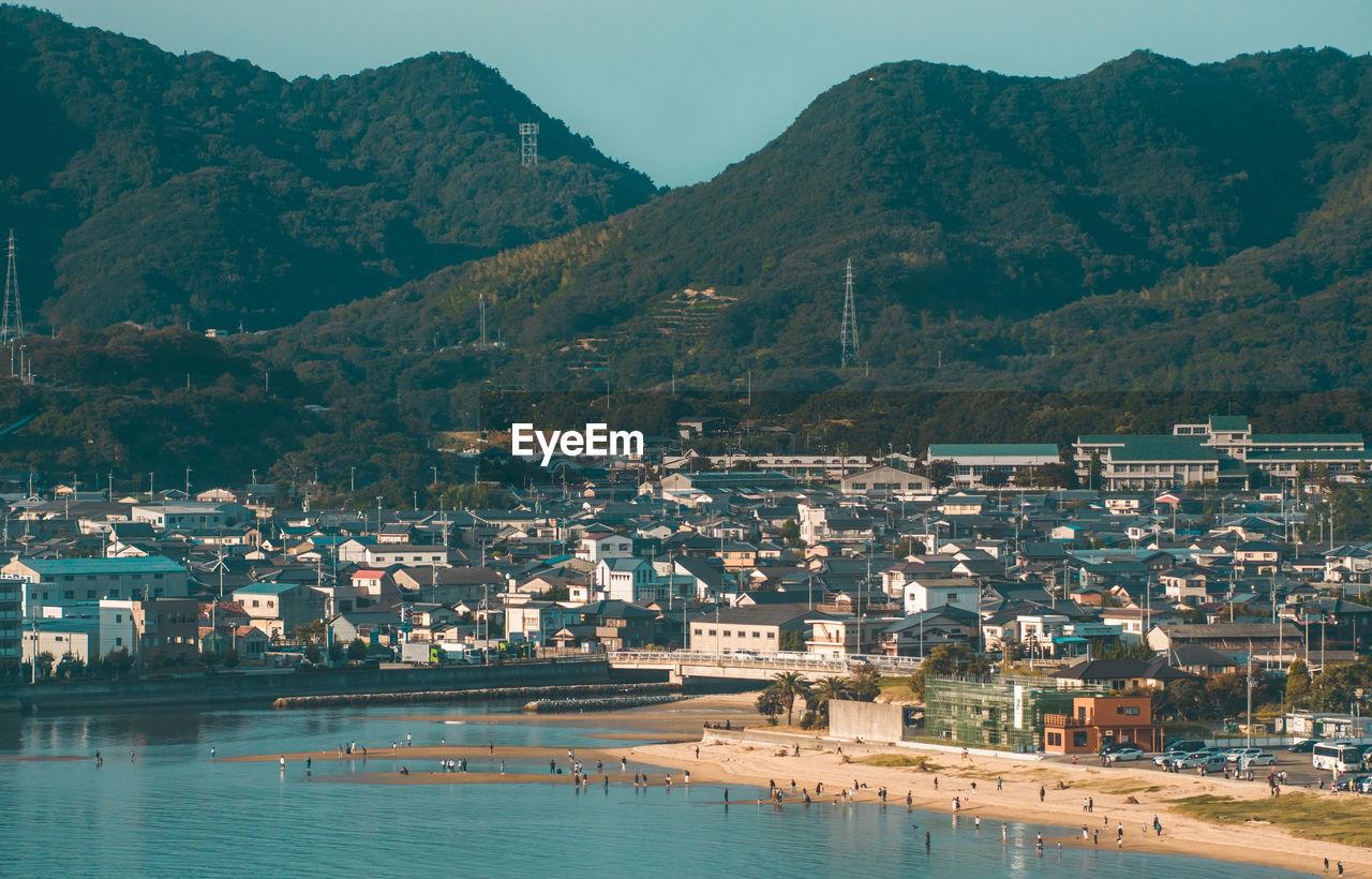 Aerial view of city by sea against mountains