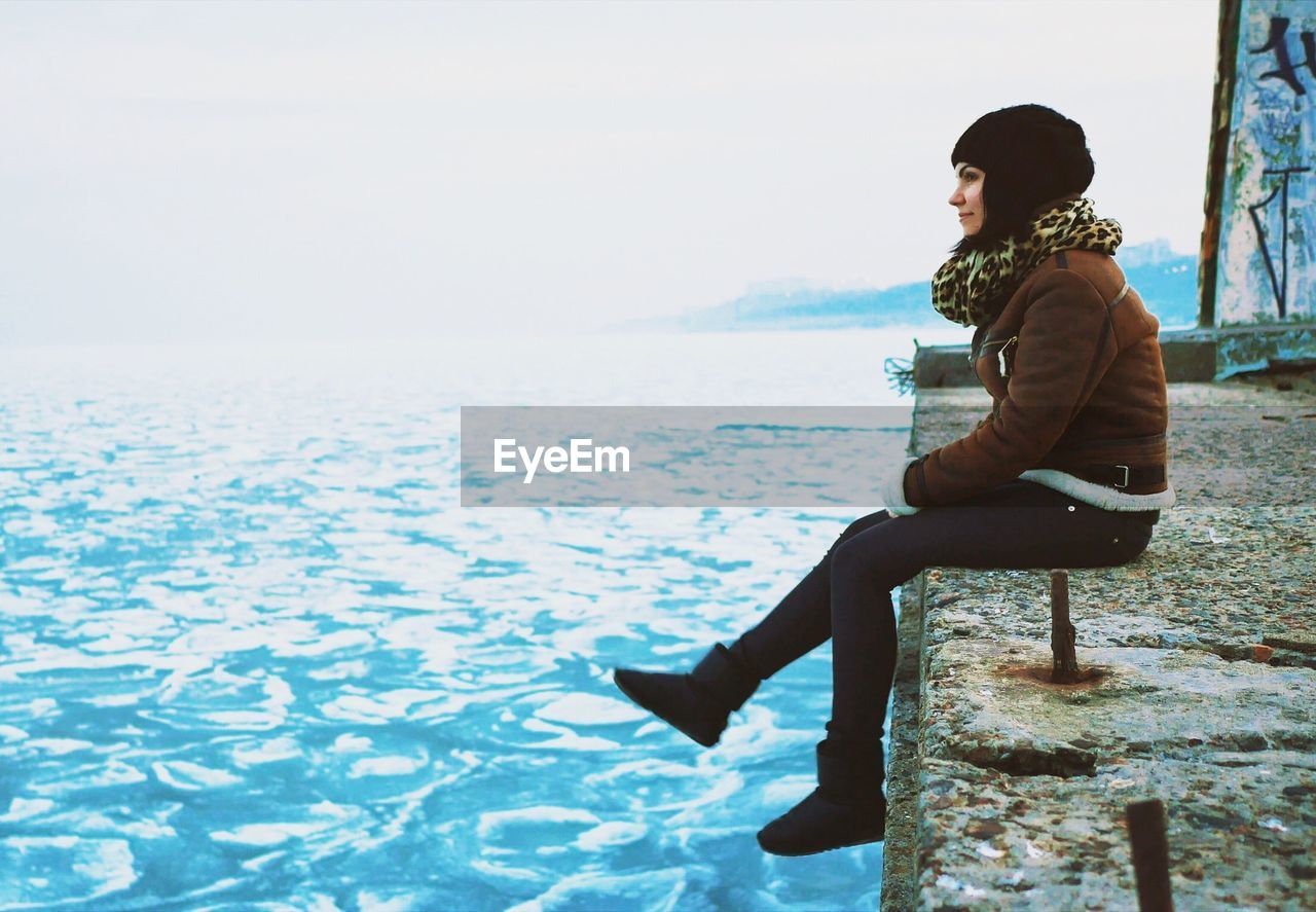 Woman sitting by water