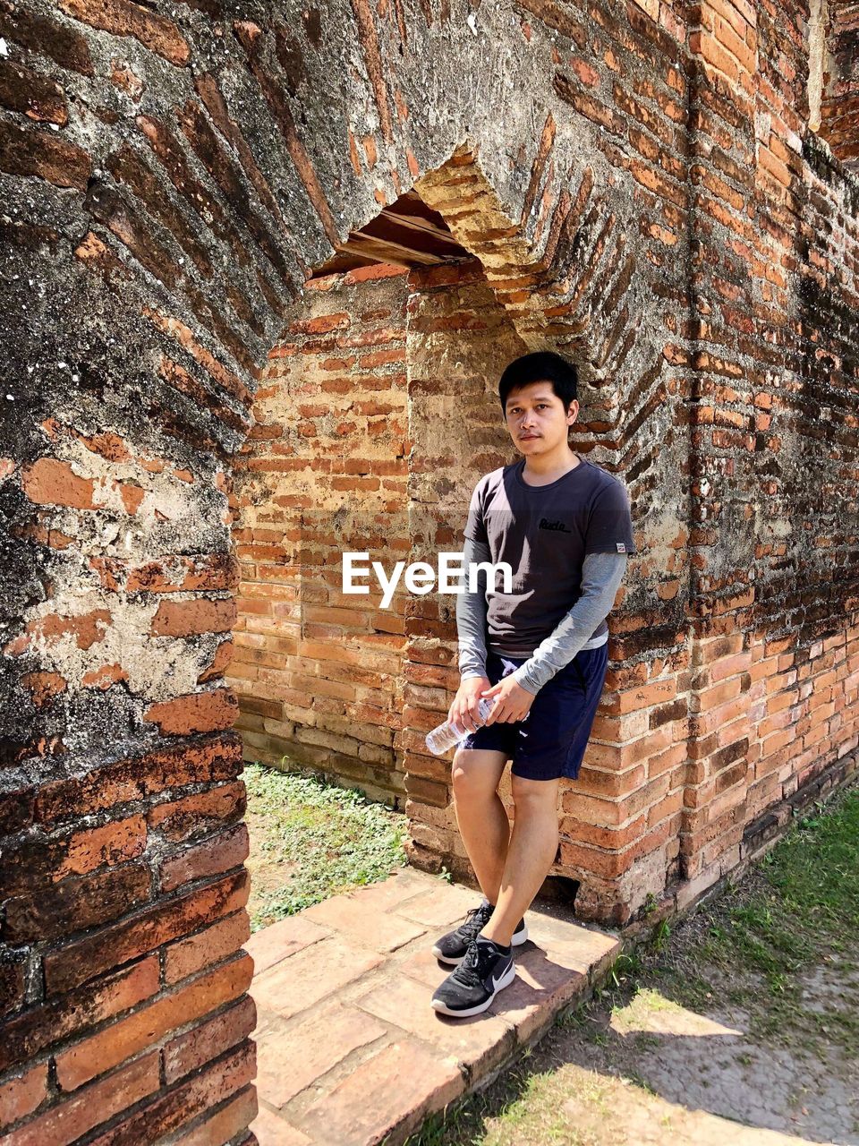 FULL LENGTH PORTRAIT OF YOUNG MAN STANDING AGAINST WALL