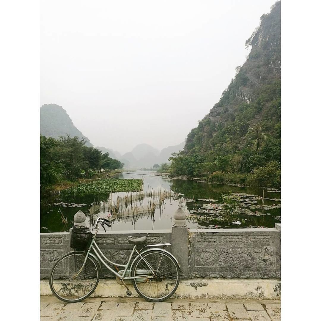 BICYCLE BY RIVER AGAINST MOUNTAIN