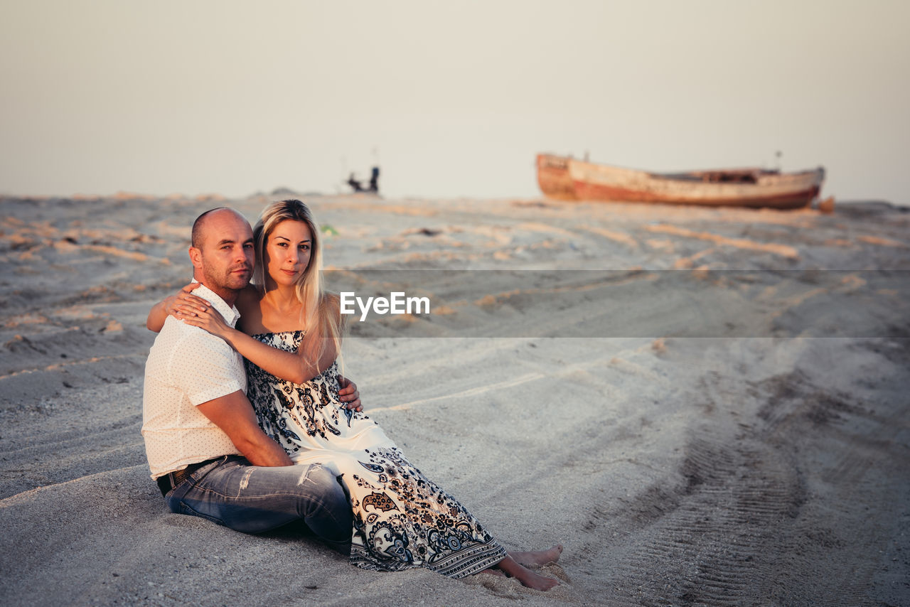 Happy young couple enjoying on a sandy beach at sunset.