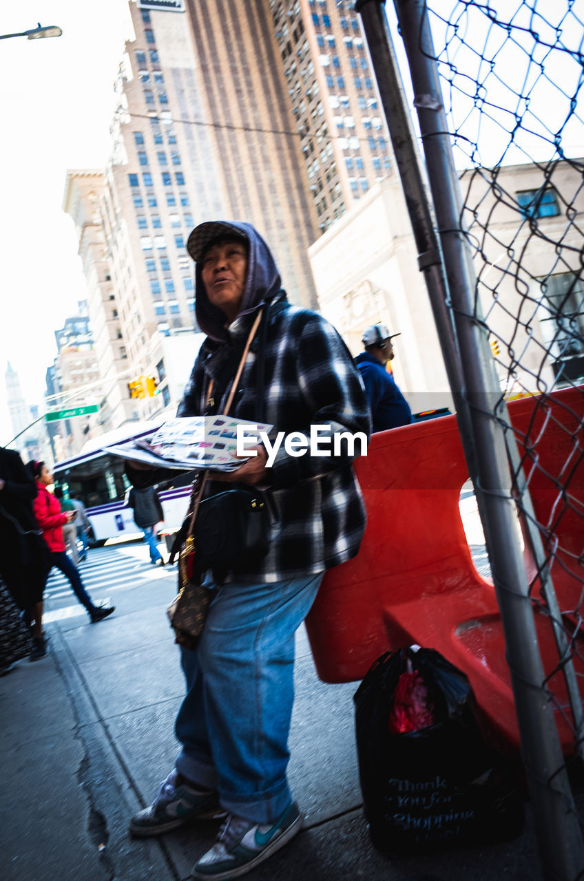 PORTRAIT OF MAN STANDING BY STREET IN CITY